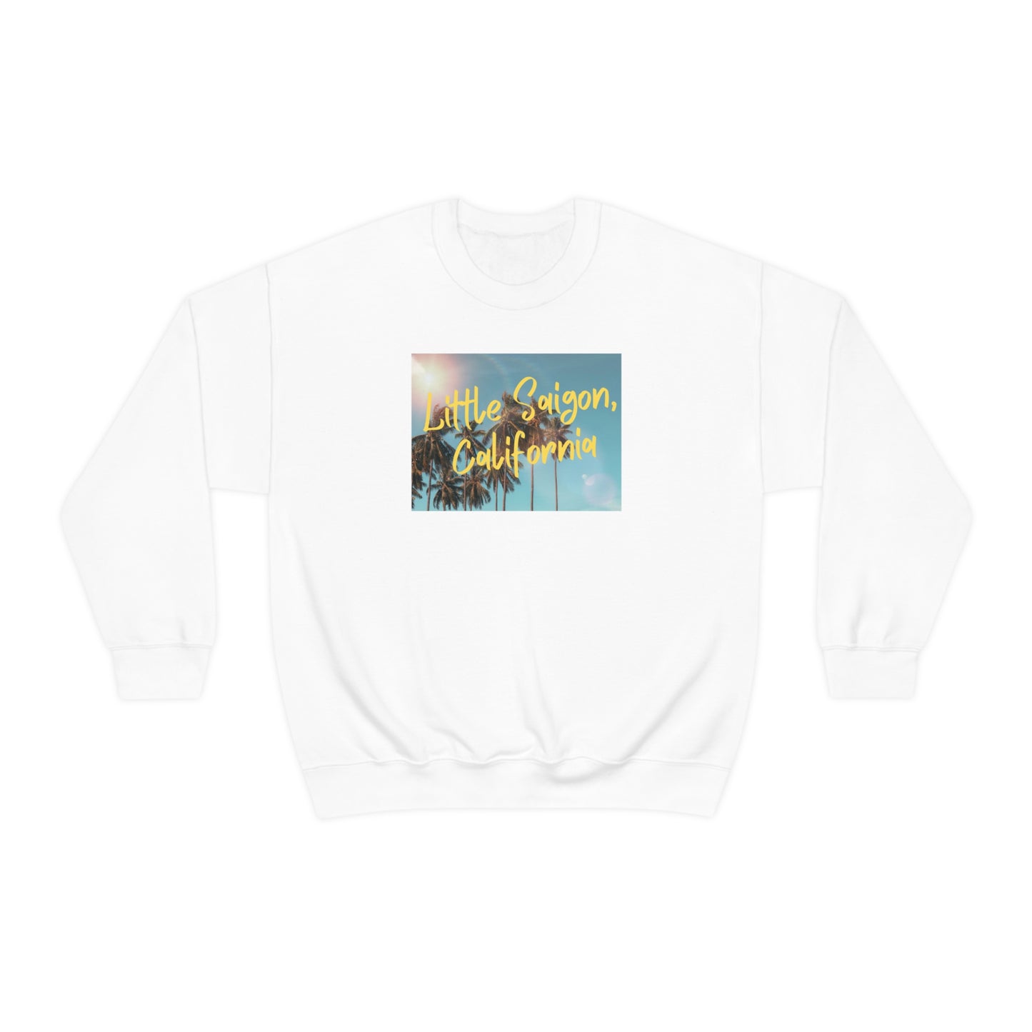 White sweater with square picture of a shining sun, palm trees, and blue sky with words Little Saigon, California written in yellow letters across the picture. Front view