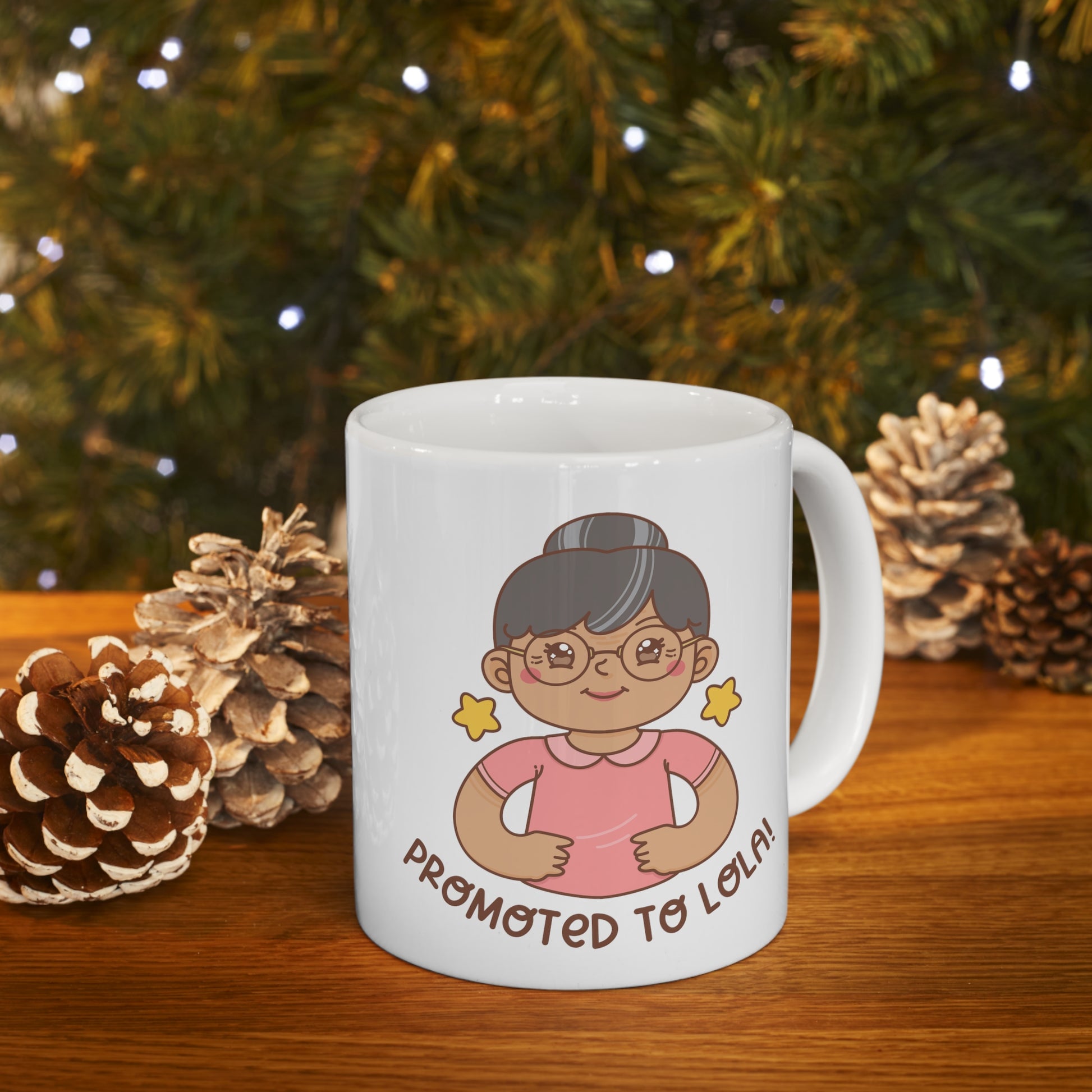 White mug with a kawaii picture of an old woman in a pink shirt wearing glasses. A caption below the picture reads Promoted to Lola! Front view