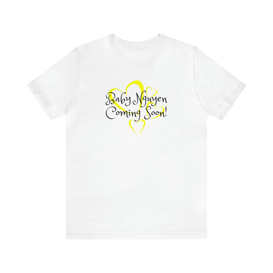 White t-shirt with Baby Nguyen Coming Soon! in black lettering with yellow outlined hearts behind the lettering.